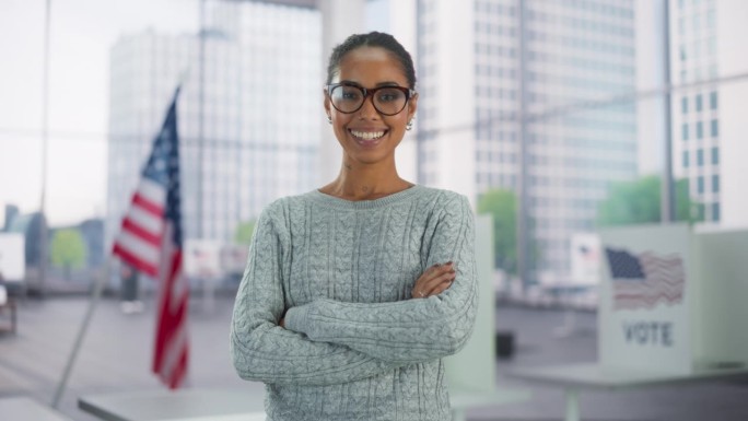 一个美丽的非裔美国女性的肖像，她以美国国旗为背景，摆出灿烂的笑容。成功的年轻黑人女性双臂交叉站在镜头