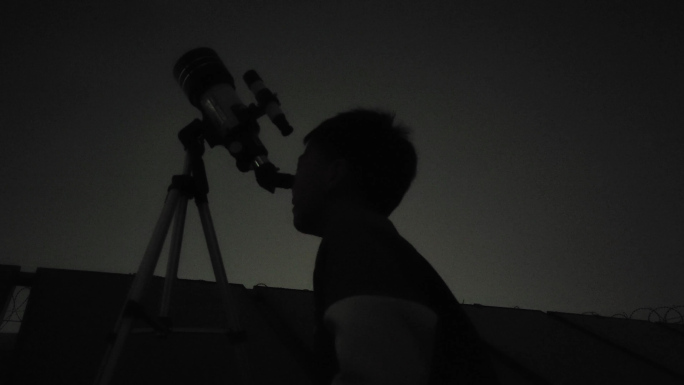 男孩用望远镜观望天空