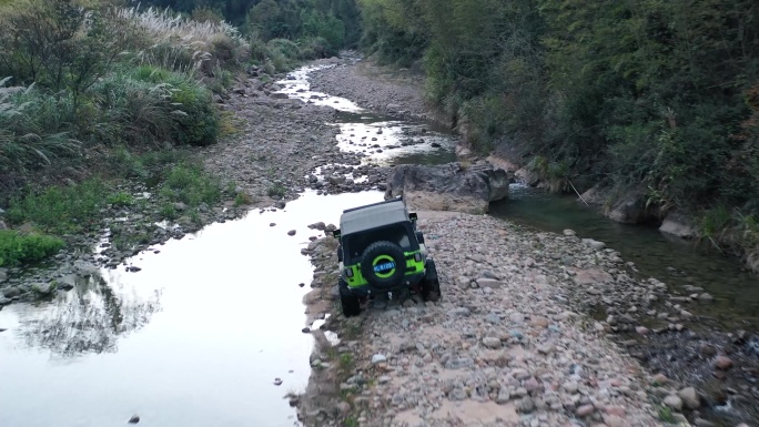 航拍越野车跋山涉水穿越河道行驶在河流石道