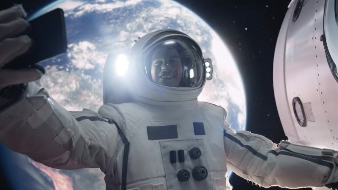 穿着太空服的人在外太空一边打电话一边抓着卫星。宇航员通过智能手机上的视频通话应用程序与任务控制中心、