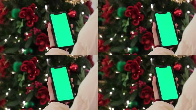 圣诞节一只手拿着绿色屏幕的手机