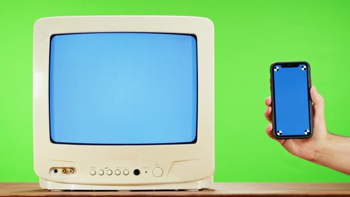绿色背景干扰屏的旧电视和蓝色色度键的智能手机。复古电视特写，怀旧。灰色噪音屏幕和故障。