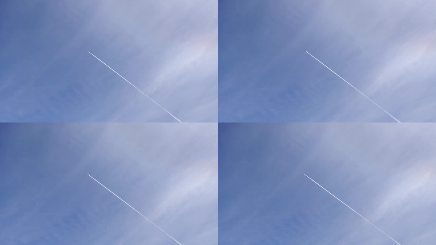 飞机在高空飞行，在淡蓝色的天空中，飞机后面有白色的尾迹或凝结尾迹