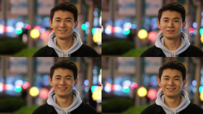 年轻中国帅哥快乐的正面笑脸，在夜晚的街头