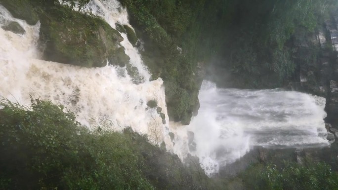 雨季的瀑布。峡谷之间湍急的瀑布河。大雨过后，泥土正在往下移。巨大翻滚的棕色浑水。4k慢动作镜头b滚拍