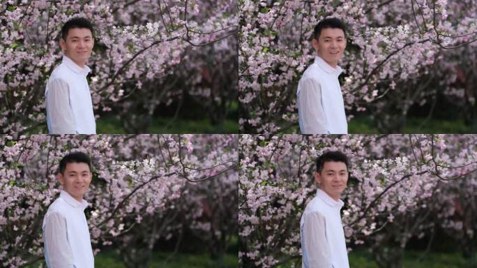 春天户外的樱花树下，年轻中国男人开心的笑
