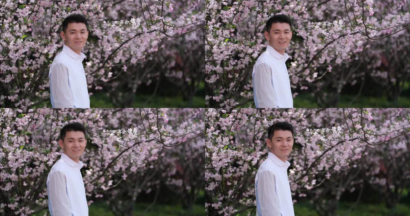 春天户外的樱花树下，年轻中国男人开心的笑