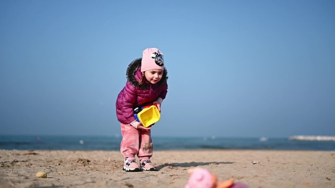 初学走路的女孩在春天的海滩上蹦蹦跳跳。