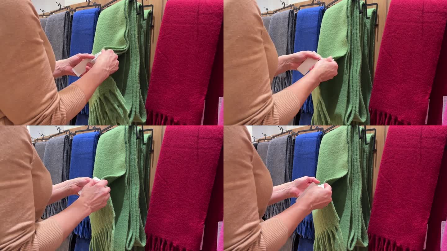 一位女士在购物中心挑选一条暖和的围巾(特写)。