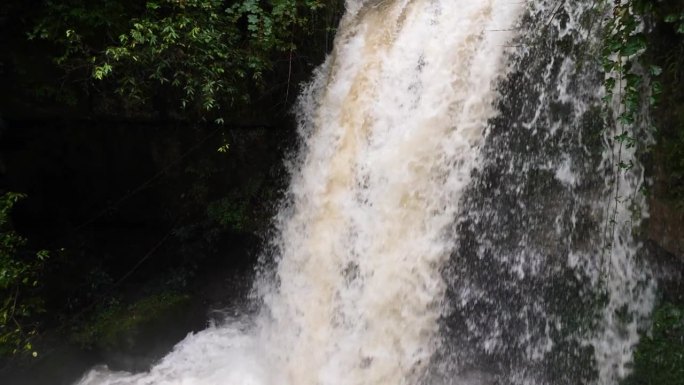 雨季的瀑布。峡谷之间湍急的瀑布河。大雨过后，泥土正在往下移。巨大翻滚的棕色浑水。4k慢动作镜头b滚拍