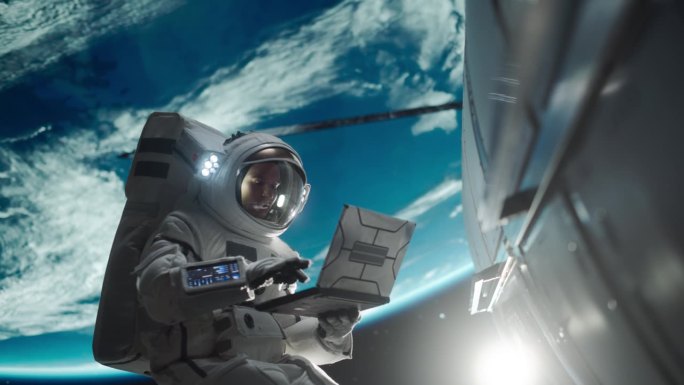 男宇航员用笔记本电脑无线连接卫星。宇航员在地球大气层外的开放空间中工作。从事维修保养工作的专业工程师