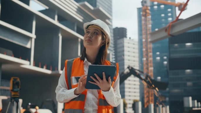 一位美丽的日本女土木工程师在建筑工地的平板电脑上工作的肖像。年轻的亚洲妇女站在户外，用电脑规划和开发
