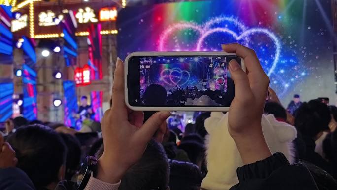 音乐晚会一个女人手棒手机拍照光束逆光剪影