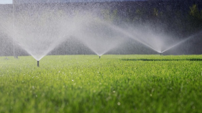 灌溉系统浇灌绿色草坪——水在压力下从喷嘴供应