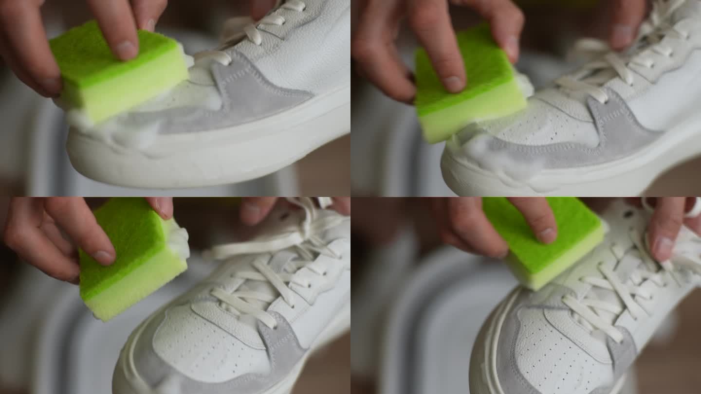 男子用海绵和泡沫洗脏白鞋的细节裁剪镜头。男性在家里用手擦拭球鞋上的污垢和灰尘。关爱鞋履的理念。