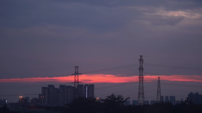 黄昏时刻红色的云飘过输电塔