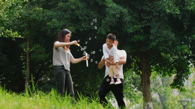 一家三口小宝宝开心在户外公园玩耍吹泡泡