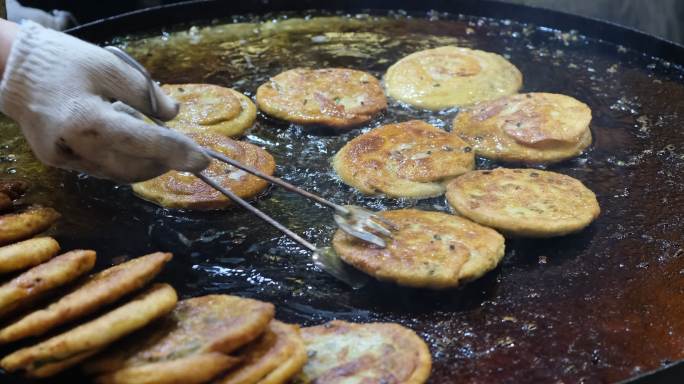 炸葱油煎饼的慢动作特写，中国传统小吃