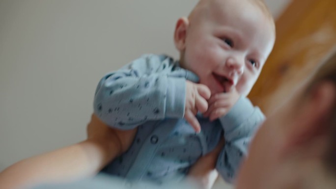 SLO - MO低角度手持拍摄母亲在家里抱起快乐的男婴