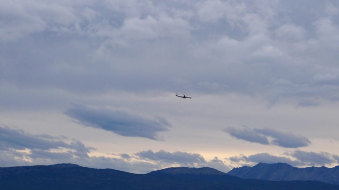 飞机在乌斯怀亚机场进场时飞过比格尔海峡，背景是被黑雪覆盖的山脉