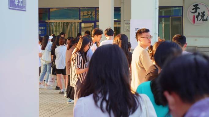 夏天落日中余晖建筑下人们大学生排队