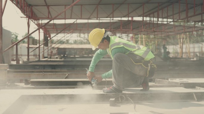 建筑工人熟练地在工地切割混凝土墙。熟练工人操作电动工具，在建筑工地切割混凝土墙-高强度劳动活动。