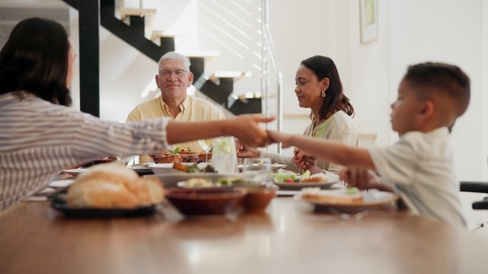 一家人，在饭桌上手牵着手祈祷，感恩食物，和上帝一起在家里。祖父母、母亲和孩子们在吃饭时祈祷，以获得精