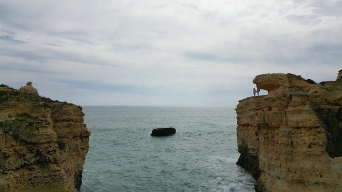 两个人在葡萄牙阿尔加维圣拉斐尔海滩哥斯拉岩用4K无人机拍摄