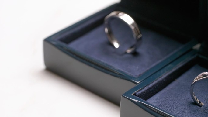 一对夫妇的订婚戒指的特写，放在一个深蓝色的天鹅绒覆盖的盒子里。