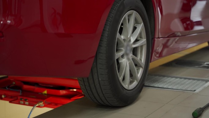 汽车技师在现代汽车维修店使用液压探测仪检查车辆悬架和转向系统。红色小车对设备进行检修检查。