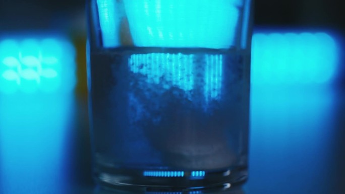 两片泡腾片溶解在一杯水中的特写，这是止痛药
