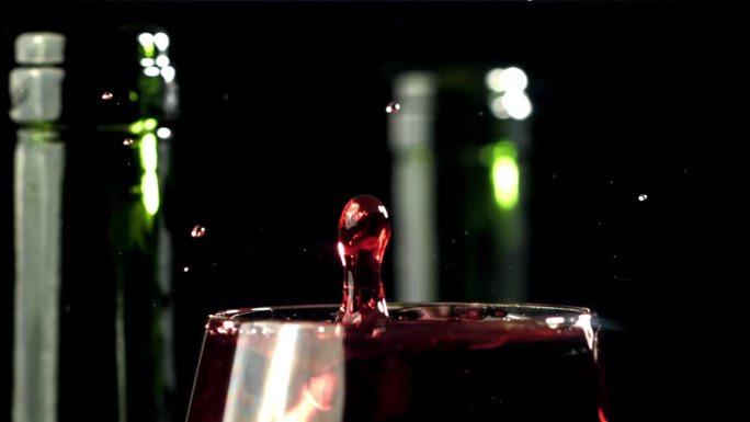 一滴水滴进了一杯酒。黑色背景。用高速摄像机拍摄，每秒1000帧。