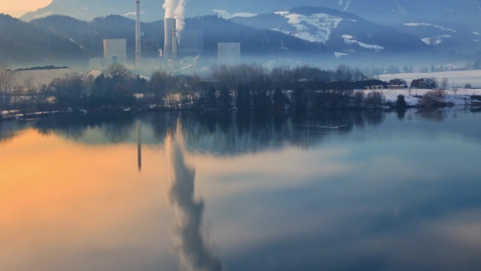 空中无人机倾斜拍摄的Velenje湖附近Šoštanj发电厂在冬天日出时对山冒烟