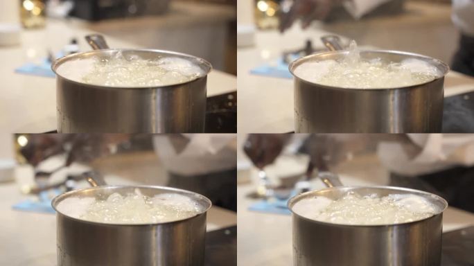 特写镜头:厨房里的电烤箱上的不锈钢汤锅里溅起了水