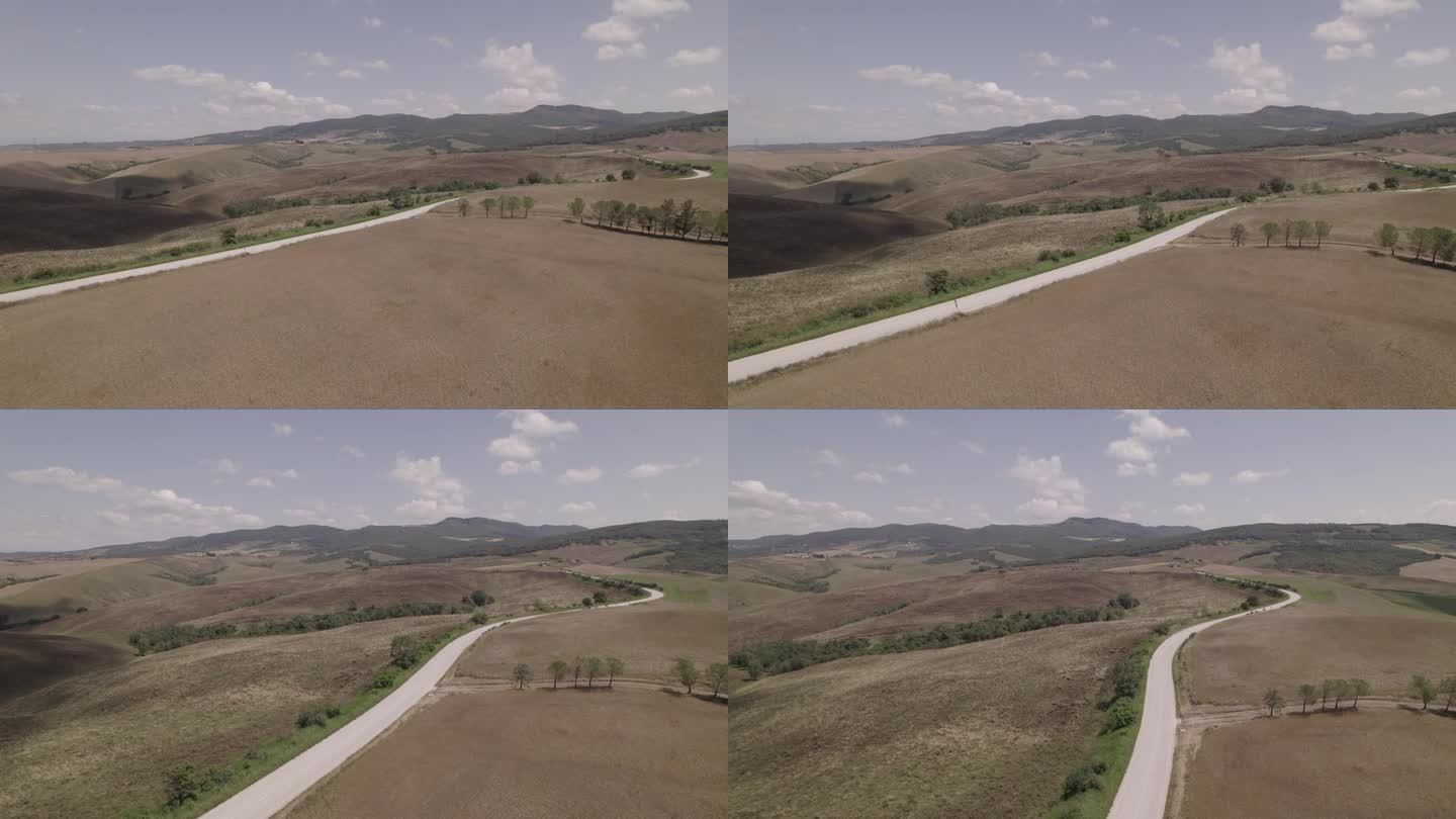 无人机拍摄的蜿蜒的道路和金色的农场在意大利托斯卡纳风景晴朗的一天，蓝天和云在地平线上LOG