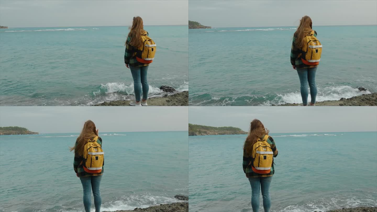 后视图，一位年轻的女游客背着双肩包欣赏着蓝绿色的海水，风吹乱了她的长发。圆周运动。