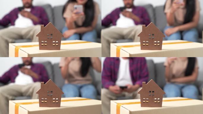 一对年轻夫妇用智能手机查找搬家信息。男女和房屋模型。