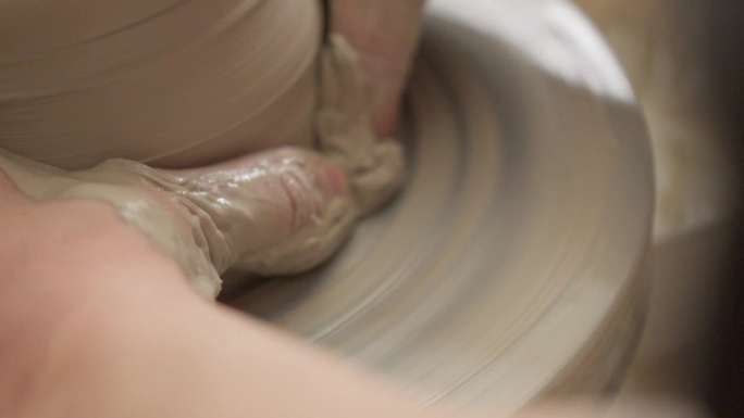 近距离观看熟练的工匠用手在制陶轮上精致地打磨花瓶的壁