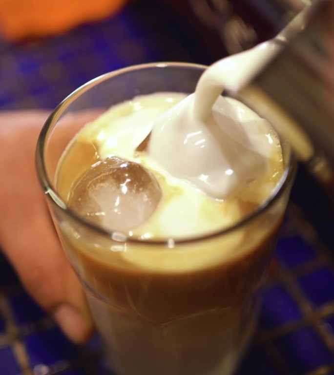 咖啡师将牛奶倒入咖啡中，制成加牛奶的冰咖啡。专业的自助餐厅。