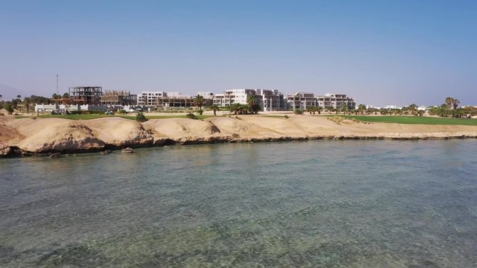罕见的空中平移无人机拍摄清澈的蓝色海洋，海岸线，和高尔夫球场在索马里湾，红海