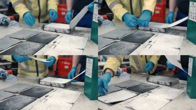 近距离观察两个工人在质量控制和条件检查方面是如何把大电池的碳层和分离层放在桌子对面的