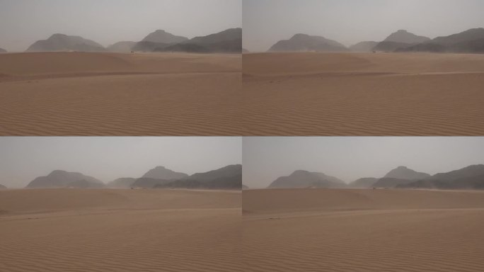 沙漠的沙尘暴。沙漠里沙丘里的沙在风中飘动。瓦迪拉姆沙漠。月亮谷。大型岩层的全景图。极端天气。