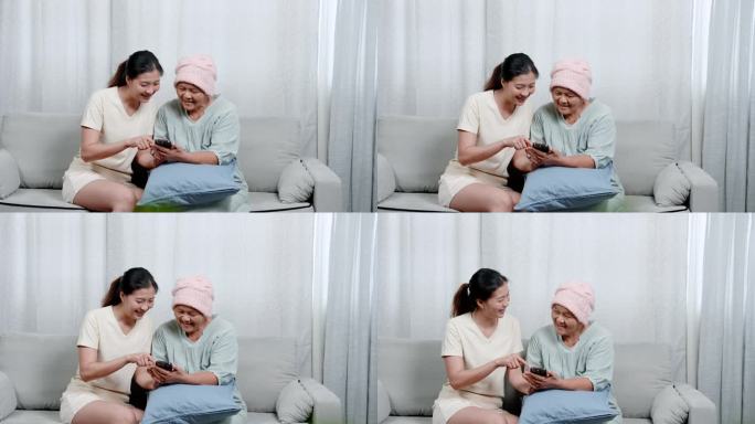 患癌症的亚洲母亲可爱的女儿，一起看手机，看手机上的搞笑片段引起笑声，空闲时间一起做的活动。