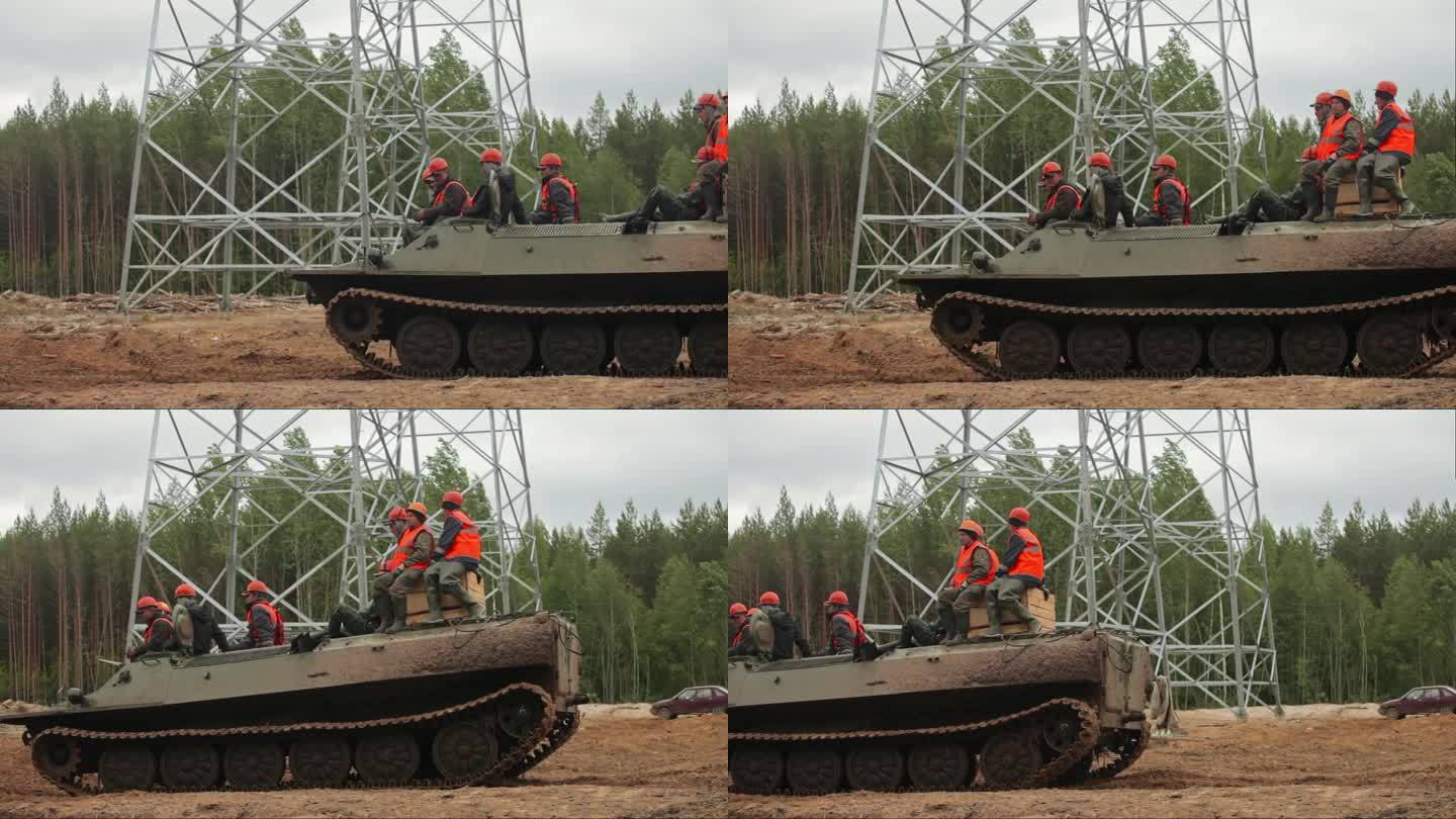 一队电工骑着一辆非军事化坦克沿着沼泽地的道路进行恢复电力的工作。