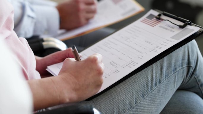 一群人坐在椅子上填写美国签证申请表