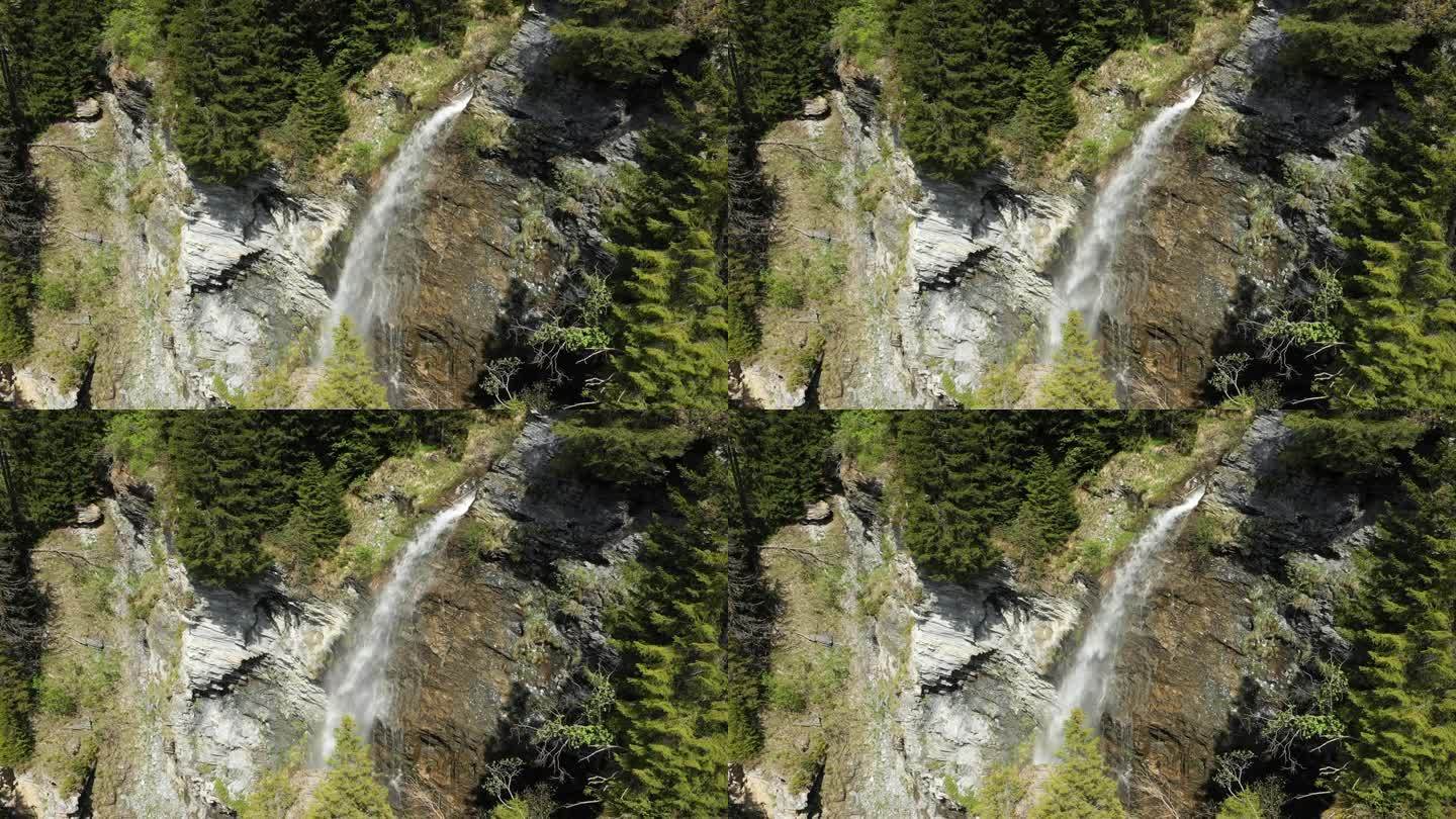 一个瀑布在绿色的森林朝着圣古萨林湖在欧洲，在法国，朝着博福特，在阿尔卑斯山，在夏天，在一个阳光明媚的