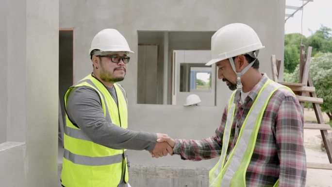 两个曾经一起工作的男建筑工程师走进来互相了解，这样他们一起工作时工作起来会更容易，在危险区域时戴上安
