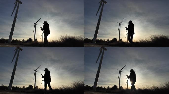女工程师手持电子平板和便携设备，在夕阳下的超广角镜头和移动摄像机中检查风能装置和涡轮机