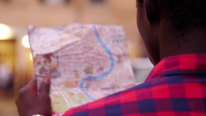 一个年轻的非洲男子试图通过看城市地图来确定自己的方位