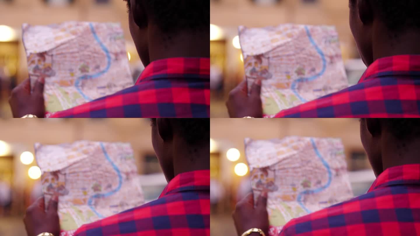 一个年轻的非洲男子试图通过看城市地图来确定自己的方位
